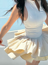 Woman in a white dress with a yellow underskirt against a blue sky.