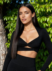 Woman wearing a black outfit standing in front of green foliage