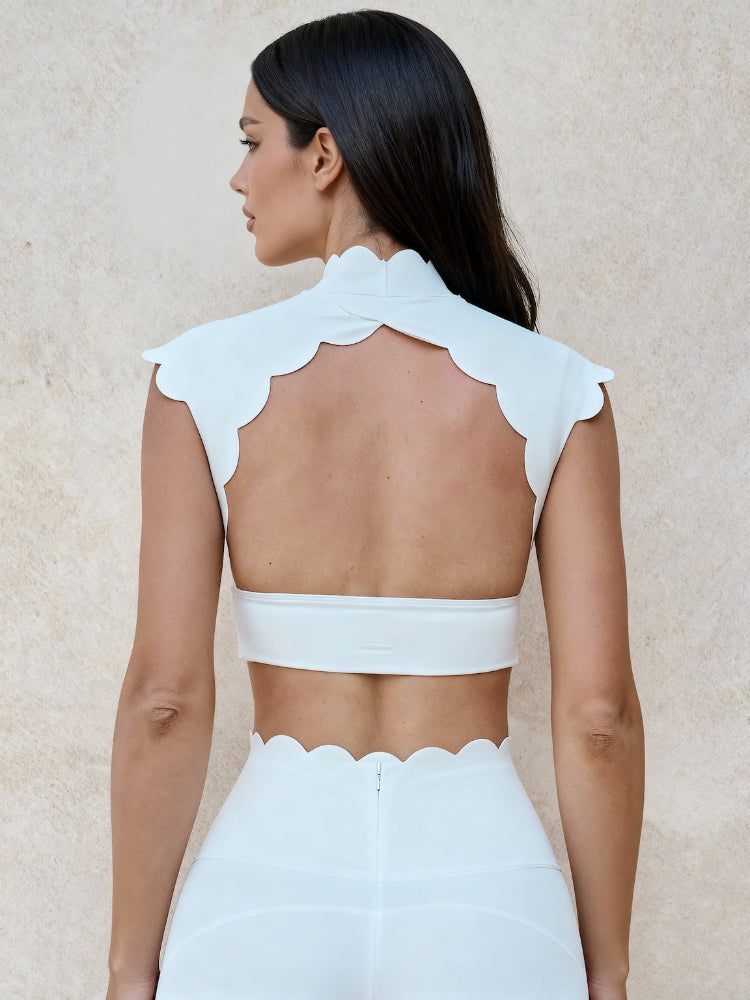 Woman wearing a white outfit with scalloped edges on a beige background
